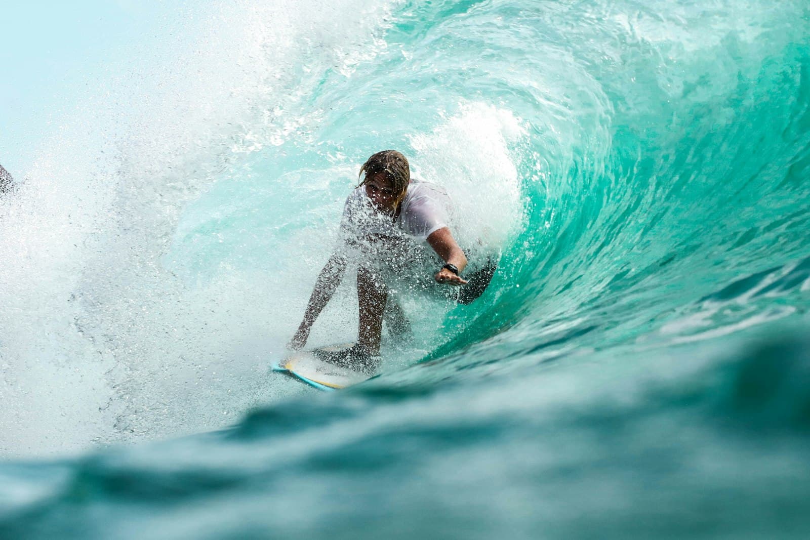 A surfer riding inside a clear turquoise wave